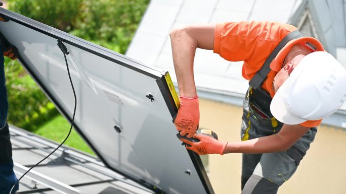 工人在搭建光伏太阳能电池板系统，用尺子测量安装设备。