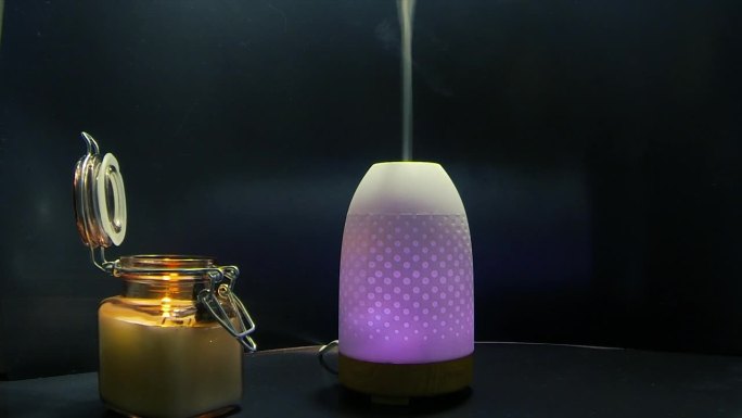 变色空气加湿器在玻璃罐中点燃的火焰蜡烛旁散发出一缕薄雾