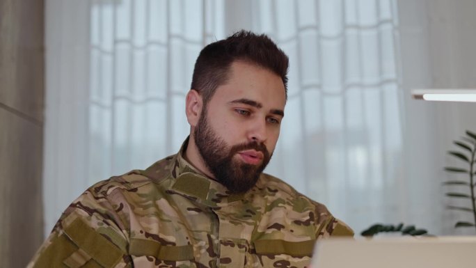 穿着军装的空军服役人员用现代笔记本电脑上网聊天。白人男性在与同事讨论即将到来的任务计划时，使用带有网