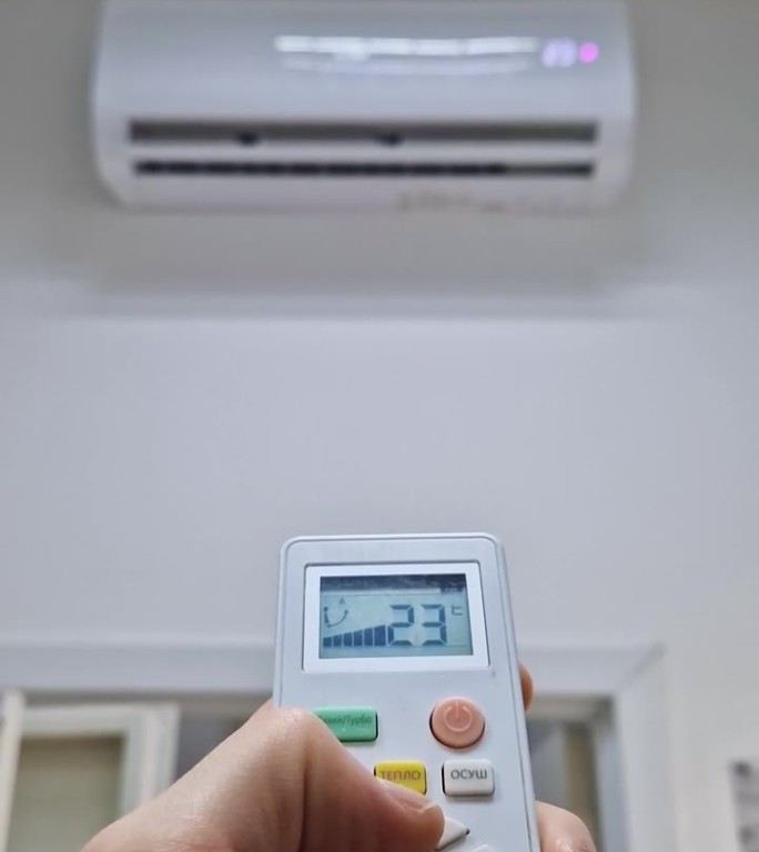 特写:男子手持遥控器，按下空调系统的按钮，试图将房间的温度调节到舒适的水平。凉爽季节的家庭供暖