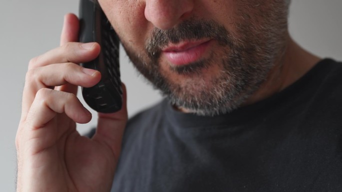 成年男子用无绳固定电话交谈的特写，男子在室内用手机交谈