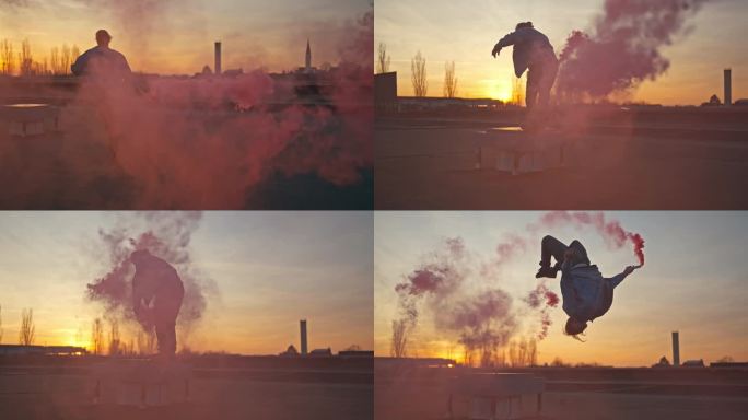 SLO MO活跃的年轻男性嘻哈舞者手持烟雾弹和做空翻在日落的屋顶