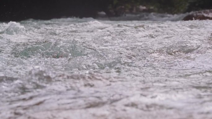 SLO MO在阳光明媚的日子里，河流急流流过岩石的表面水平锁定镜头