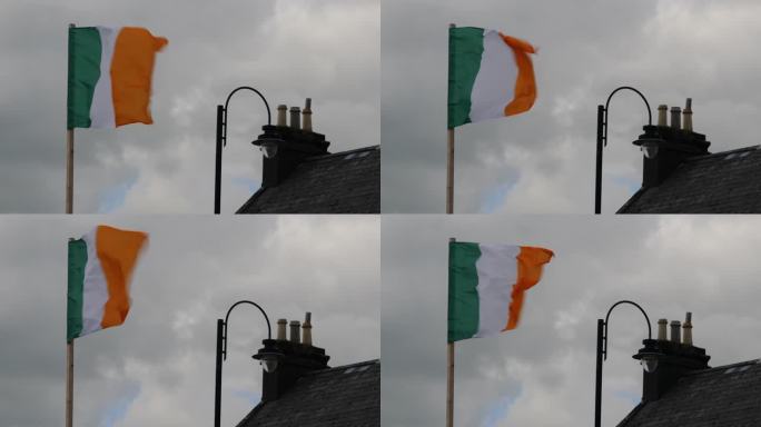 爱尔兰国旗舞在多云的天空和传统的屋顶