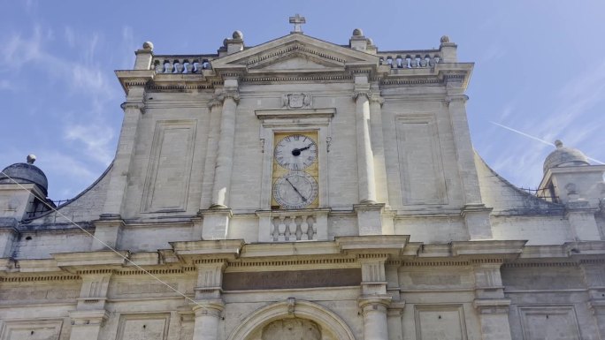 在法国的一个小镇上，一座用砂岩建造的教堂前，有一座大钟，一些柱子和装饰品