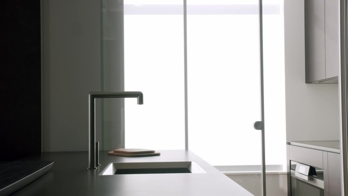 现代厨房的水槽配有水龙头，家用电器和玻璃推拉门
