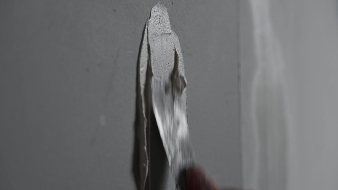 用油灰和油灰刀在墙上填洞。