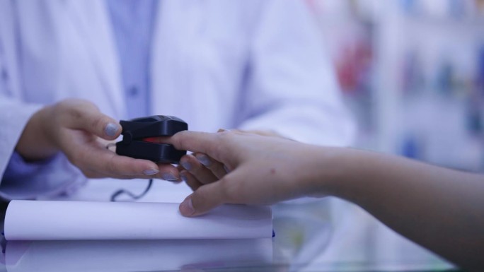近距离药剂师在药房使用测氧工具或脉搏血氧仪测量患者手指的血氧。