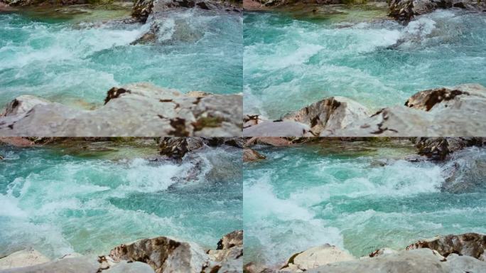 在阳光明媚的日子里，河流蓝色的急流流过岩石的高角度平移镜头