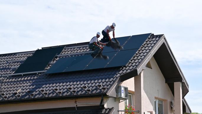 工人们在屋顶上建造太阳能电池板系统。安装光伏太阳能组件的工人