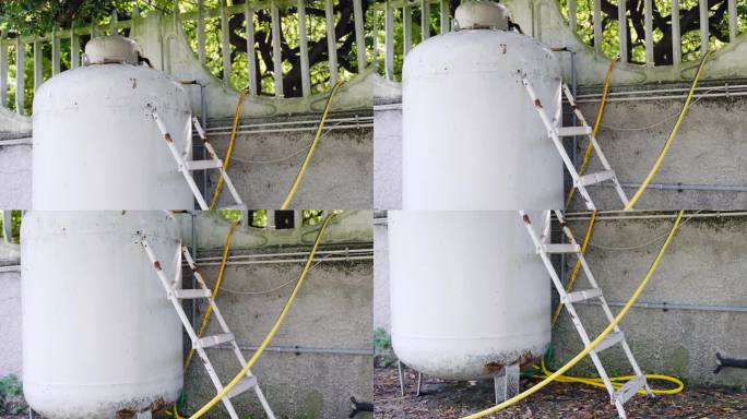干净的储水罐用梯子和黄色的管道放在花园里，水箱在没有水供应的情况下抽水到房子里，水泵靠电工作