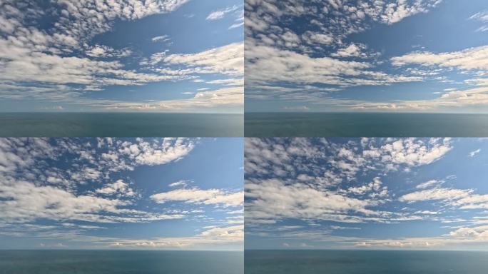 在平静的海面上，蓝色的夏日天空中飘动着飘忽的蓬松积云。抽象的空中自然夏季海洋日落，大海和天空的看法。