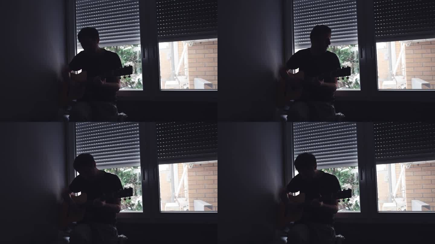 一个人在黑暗的房间里用原声吉他弹奏音乐