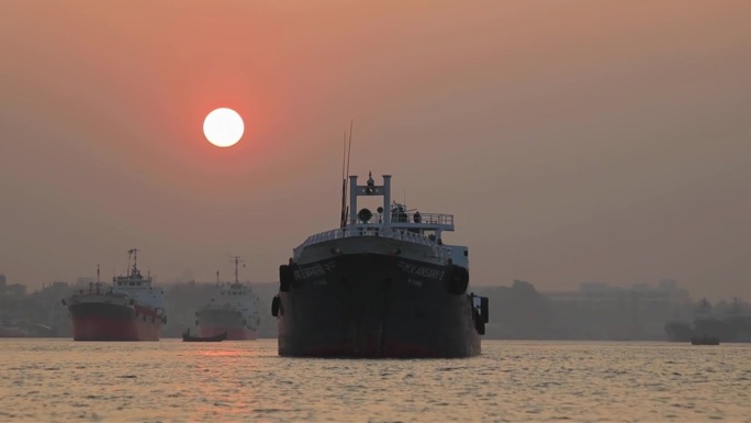 日落时分，孟加拉国吉大港水上的重型集装箱船