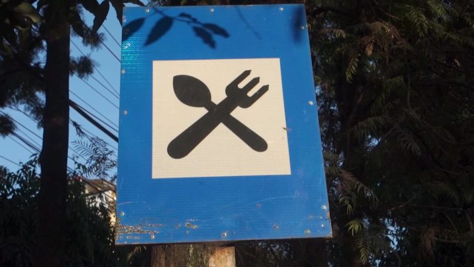 路边餐馆:印度北阿坎德邦德拉敦市路边的蓝板上的叉子和勺子标志