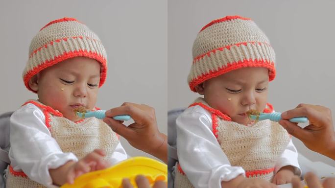拉丁裔婴儿不想吃用勺子递给他的食物。婴儿的第一种固体食物