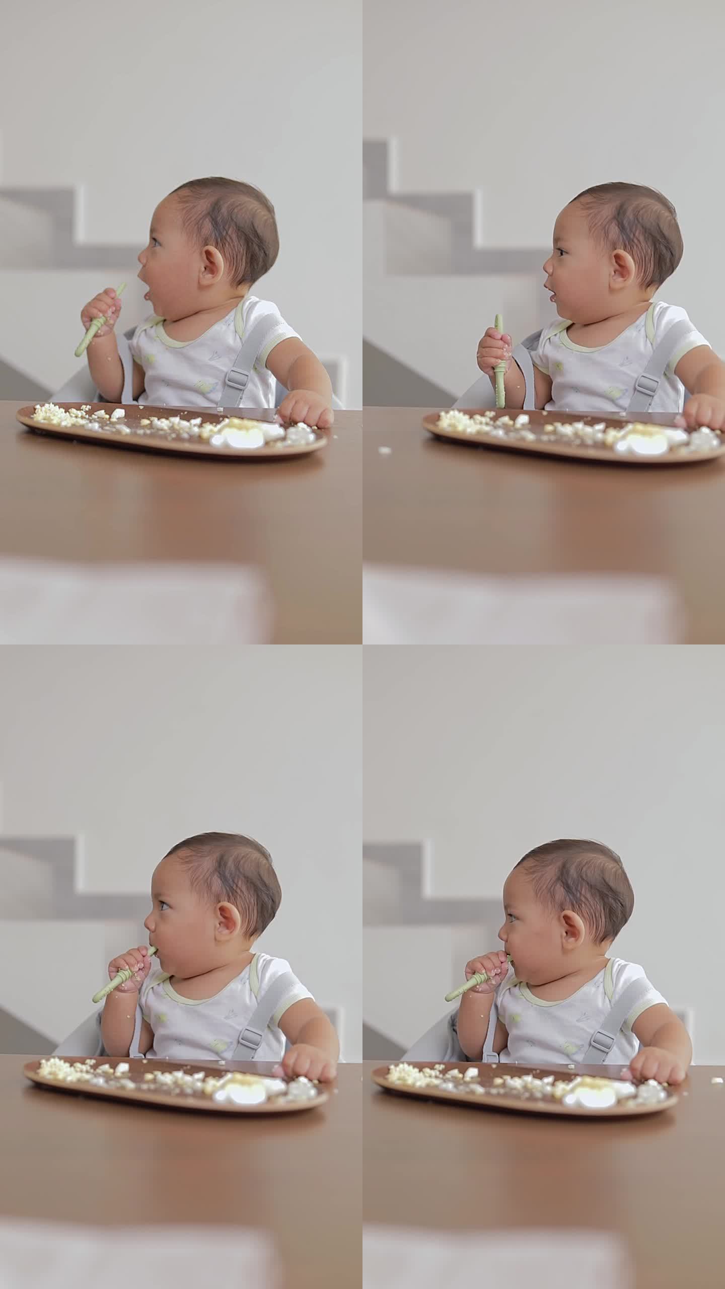 拉丁裔婴儿坐在桌子旁吃饭时嚼着勺子