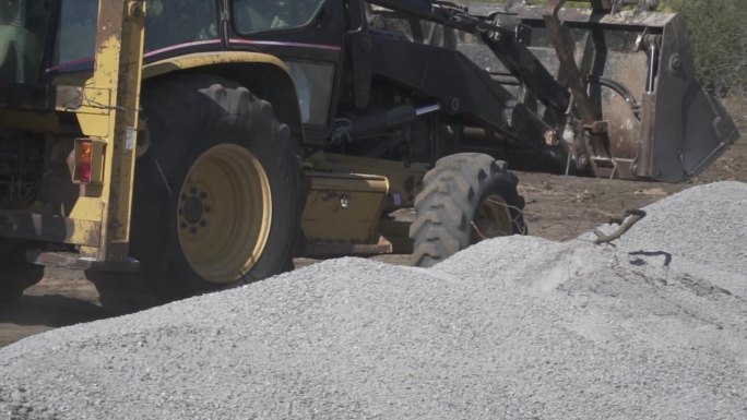 拖拉机挖土机正在一处工地的碎石堆周围行驶