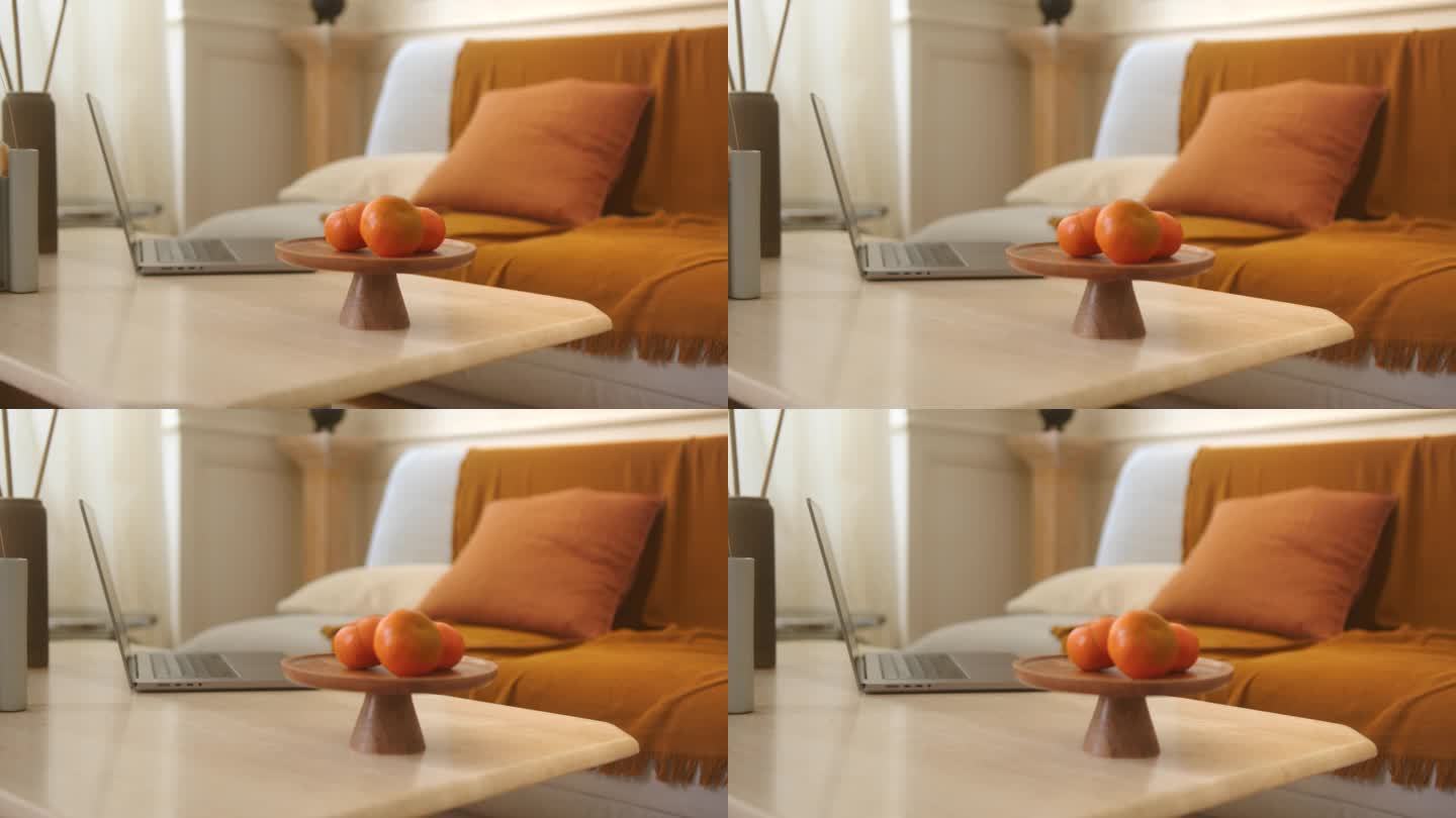 客厅的桌子上放着橘子和一台笔记本电脑