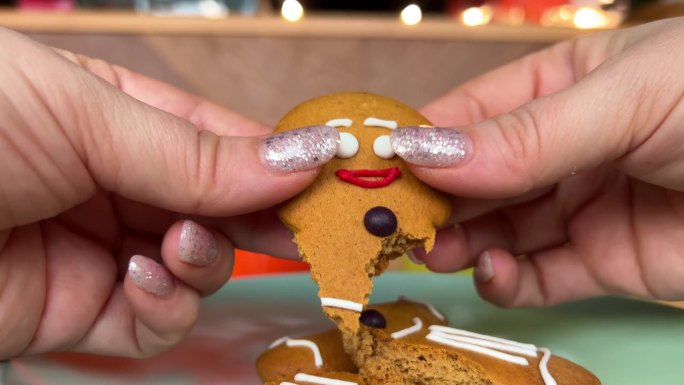 把姜饼人掰成不同的部分摧毁了生命结束的概念节日节日饼干在一个女人的手中结束了圣诞节