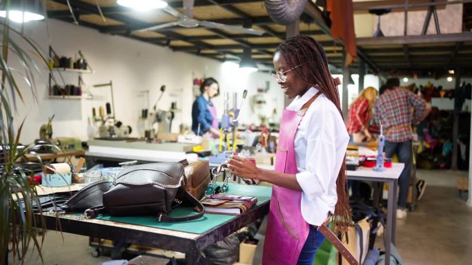 年轻的黑人女裁缝展示她制作的现代皮包