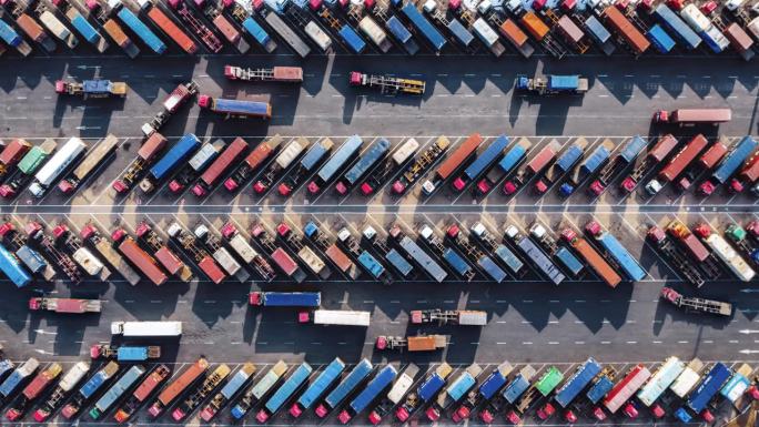 T/L鸟瞰图，在港口行驶的一排排卡车和拖车