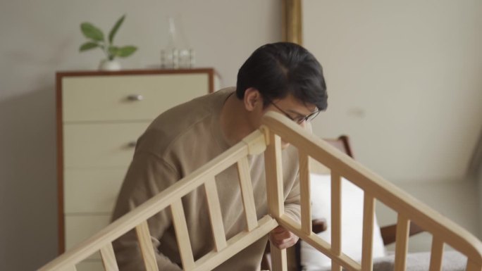 亚洲男子在育婴室组装DIY婴儿床