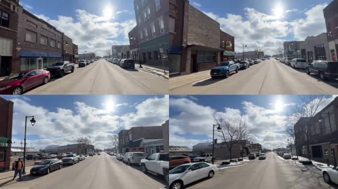 汽车视角拍摄:在一个晴朗的日子里，天空中有云，在Oelwein的一条主要道路上开车经过当地的企业