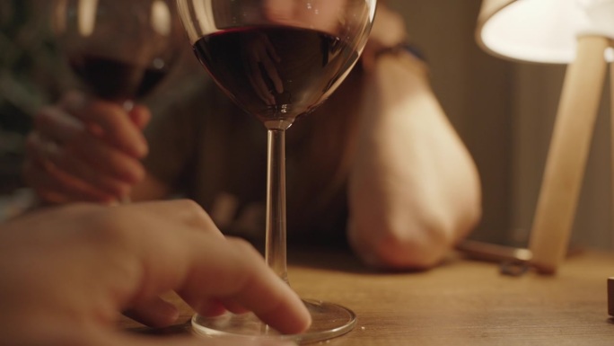 餐桌上的两杯红酒特写，一场浪漫的约会，一个女人在背后喝酒。