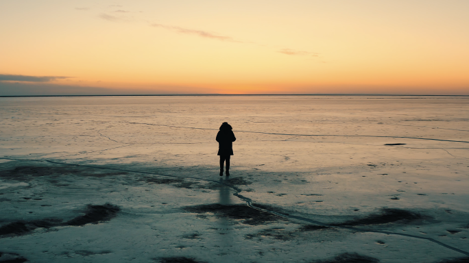 航拍夕阳下人物在冬天冰面前行