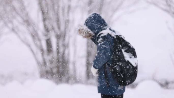 快乐的小男孩在上学的路上玩雪