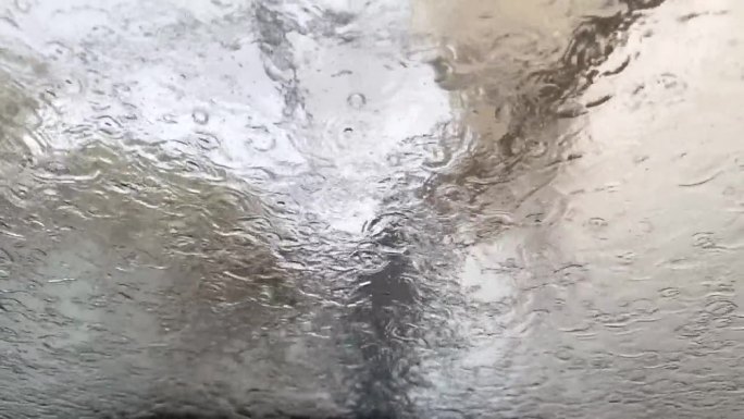 男子用加压射流清洗汽车挡风玻璃。在人工洗车服务中，流动的水模糊了玻璃。从内部近距离观察。高质量的全高