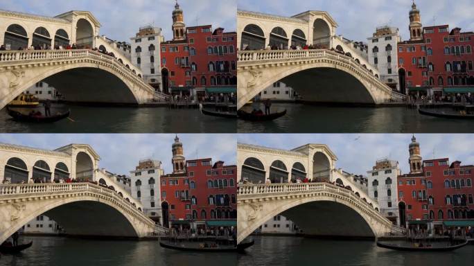 意大利威尼斯历史悠久的里亚托桥上挤满了游客，游客们看到贡多拉传统船只在运河上驶过