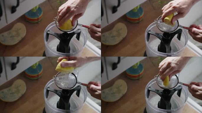在农家乐的厨房里，在自然光下，一只手从台面上拿起半个柠檬，把它挤进滤网，放在食品加工机的上面