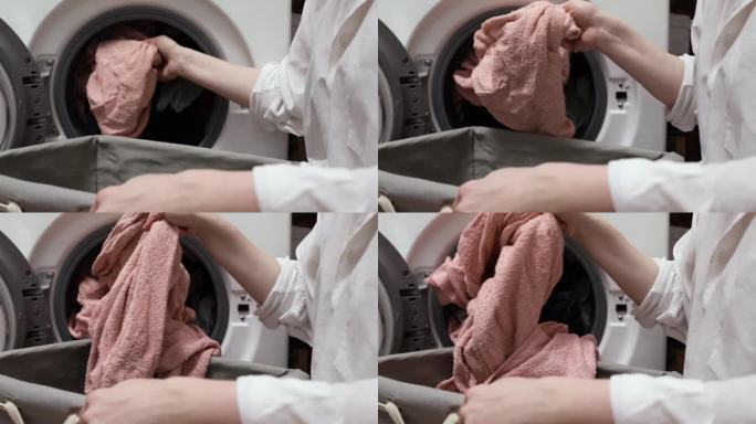 洗衣，一个女人从洗衣机里拿出湿衣服，把它们放在洗衣篮里