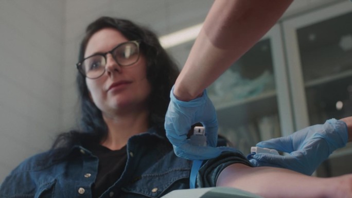 从一个女孩身上采血。女实验室助理给女病人手臂上缠止血带