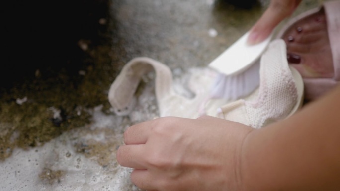 给孩子洗鞋子，用刷子刷洗。