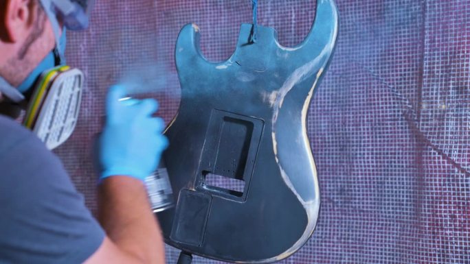 男子用蓝色画电吉他的琴身。4k视频片段UHD 3840x2160