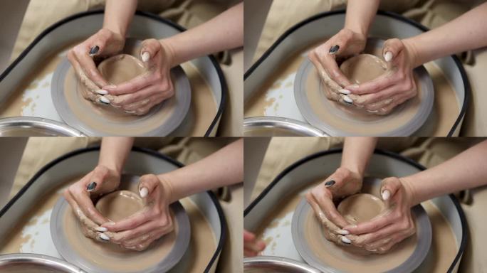初学制陶的人。女性的手，长指甲交叉在粘土上
