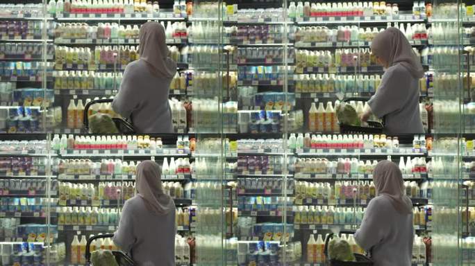 4K穆斯林妇女在超市的冷藏柜里挑选牛奶