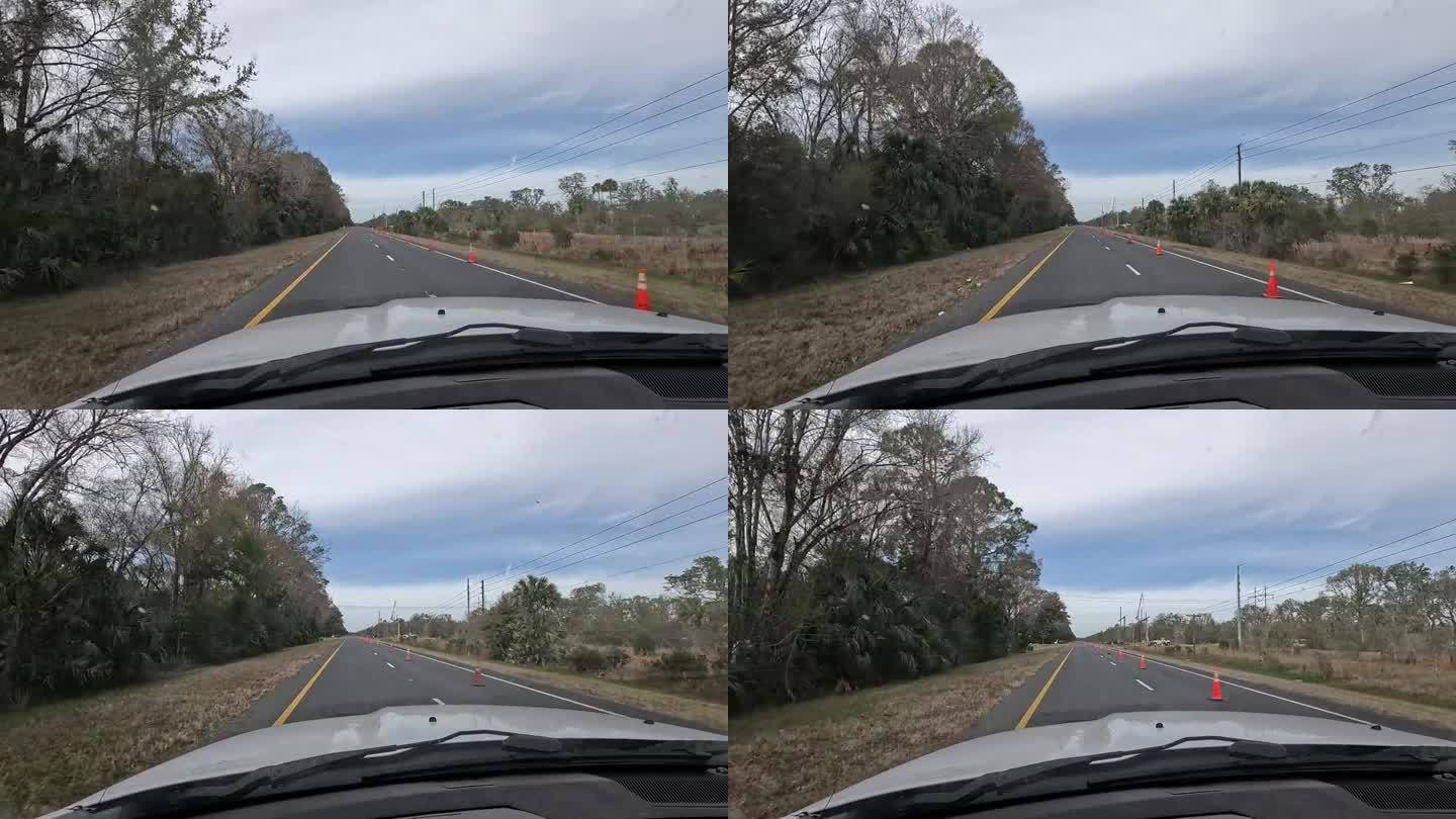 驾驶员在空旷的公路上行驶时的景象，道路施工橙色锥形锥体将交通合并成一条车道