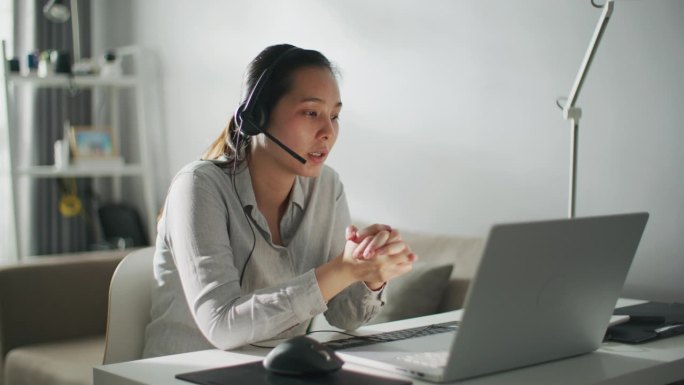 微笑的女商人戴着耳机在笔记本电脑上进行会议视频通话