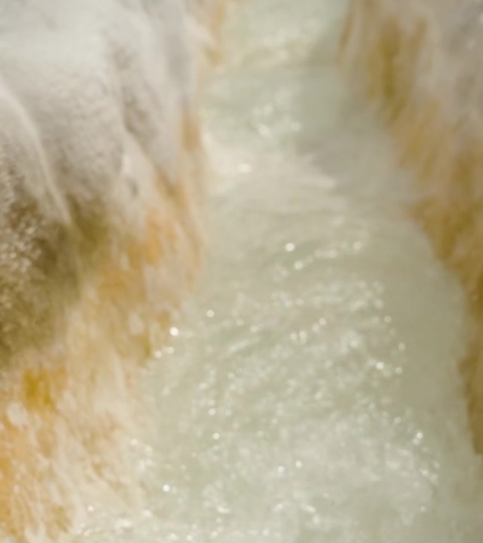 垂直视频。方解石钟乳石，一种白色的石质通道，形似峡谷，纯水从泉中流过，Pamukkale。慢动作。