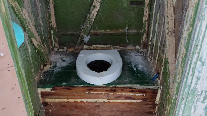 一个又旧又脏的乡村厕所的洞，乡村厕所里面