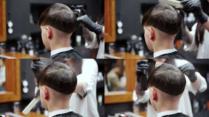 专业发型师在理发店用发胶为男孩梳理发型。孩子现代发型与吹风机，美发工具反映在镜子。梳理会议，理发店的