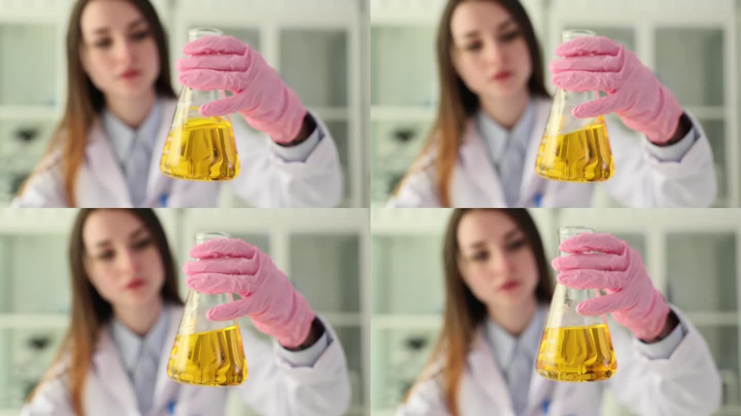 女化学家检查玻璃烧瓶中的黄色油液