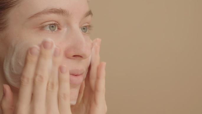 四分之三的年轻女子用洗面奶洗脸。皮肤护理