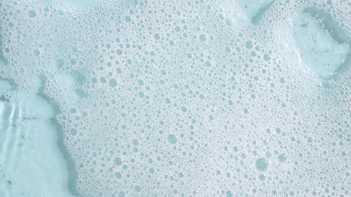 白色的肥皂泡在蓝色的背景上。沐浴皂泡沫。肥皂泡的质地。天然白色洗发水泡沫运动