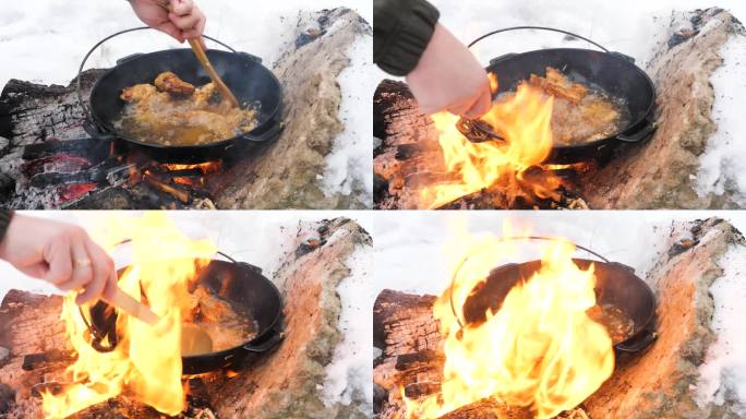 冬雪中，男子在明火上用木铲在金属锅里翻炒炸鸡翅。在野外烹饪，在寒冷中与大自然独处。