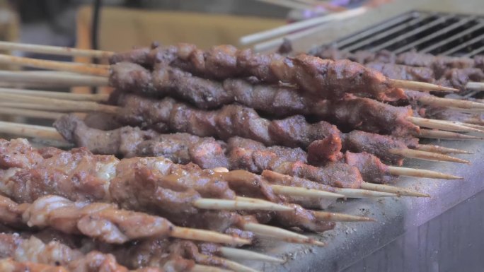 用木棍在烤架上煎肉的特写镜头。亚洲美食。